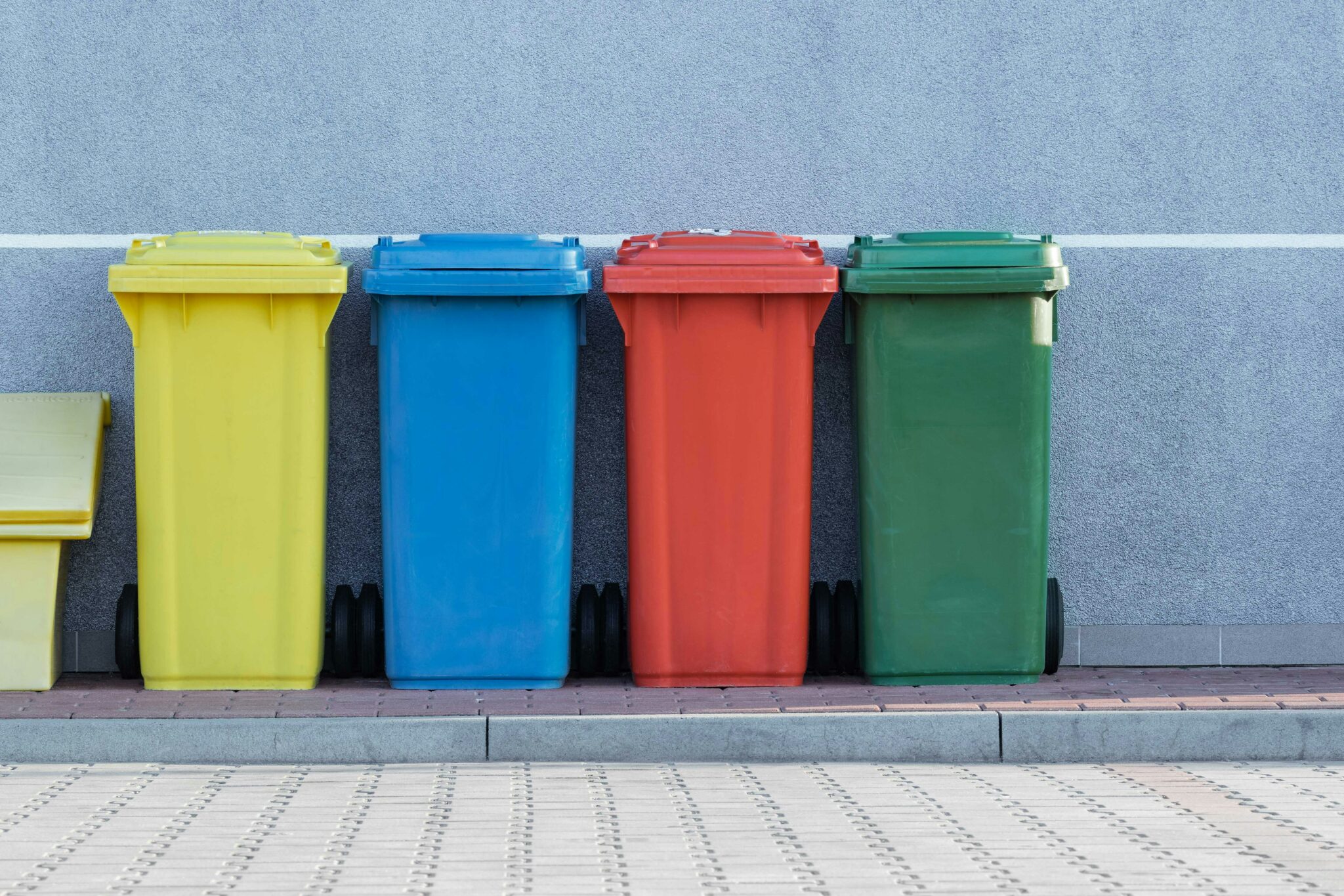 A collection of different coloured commercial wheelie bins